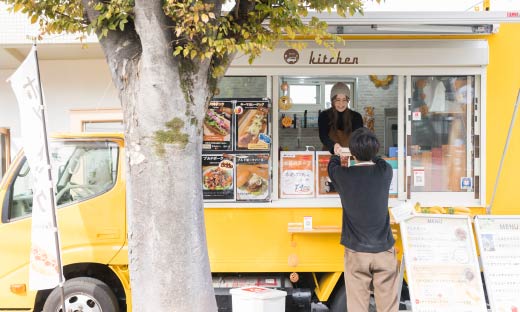 キッチンカーで食べ物を渡す店員と受け取る客
