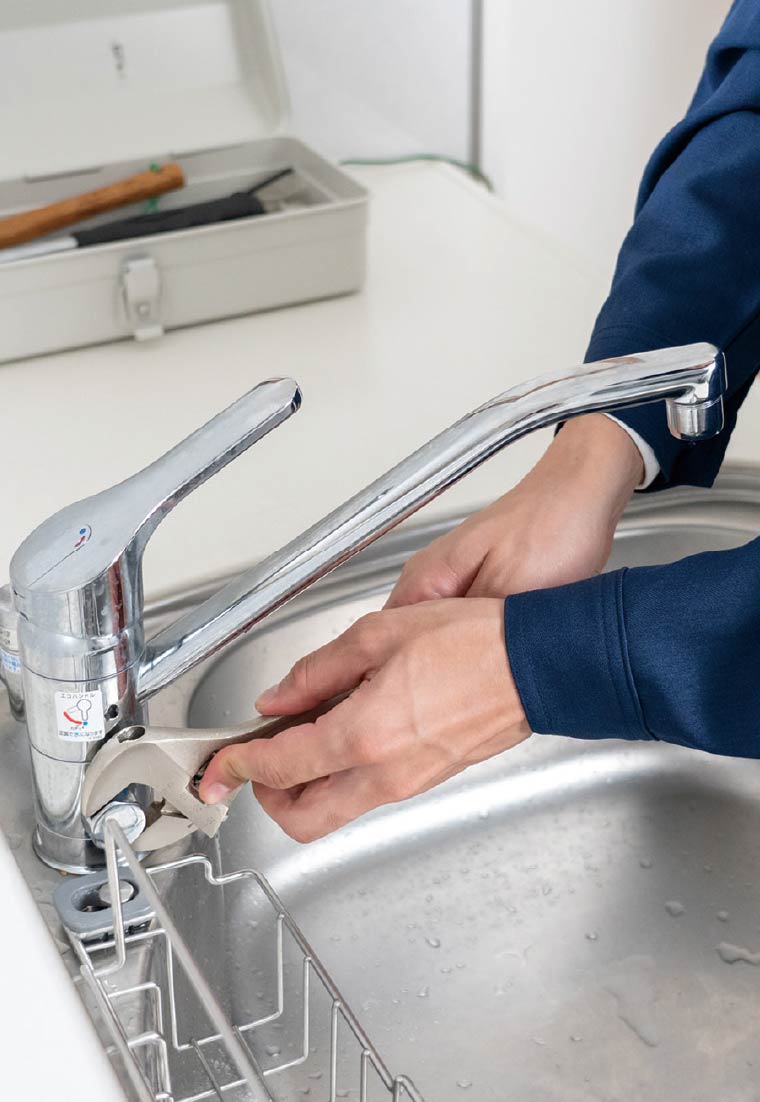 キッチンの水栓を修理している作業員の手元